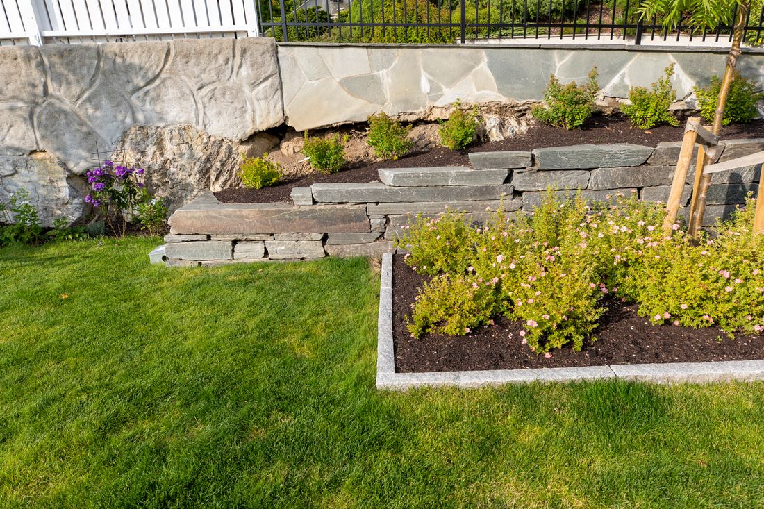 Mur av naturstein, granittsteinkant, beplantning